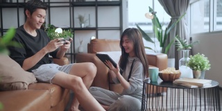 家庭隔离隔离，亚洲夫妇坐在放松使用笔记本电脑和平板电脑社交媒体或网上购物冲浪在客厅的家庭室内背景
