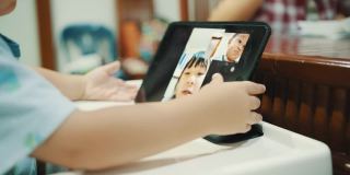 蹒跚学步的孩子在家里用数字平板电脑进行视频通话。