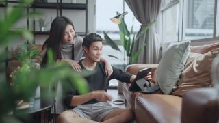 家庭视频通话，亚洲夫妇使用平板电脑在封锁期间与他们的家人在客厅沟通，家庭隔离保持联系，家庭内部背景视频素材模板下载