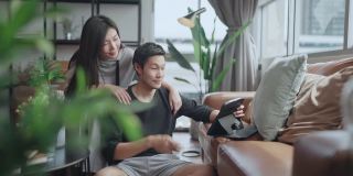 家庭视频通话，亚洲夫妇使用平板电脑在封锁期间与他们的家人在客厅沟通，家庭隔离保持联系，家庭内部背景