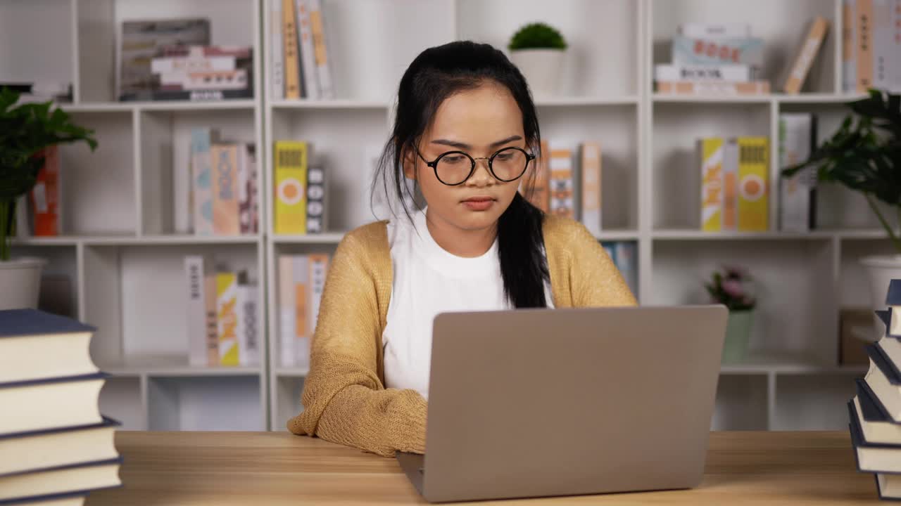 疲惫的亚洲女孩眼镜工作与笔记本电脑