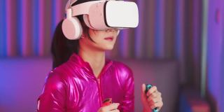 年轻的亚洲女性正在使用虚拟现实耳机。霓虹灯工作室肖像。虚拟现实、模拟、游戏和未来技术的概念。亚洲女人在卧室里玩游戏。