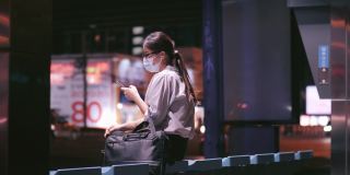 一名女子晚上在公交车站使用智能手机