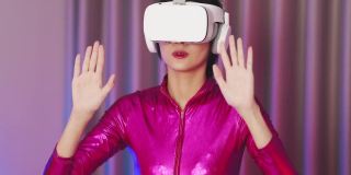 年轻的亚洲女性正在使用虚拟现实耳机。霓虹灯工作室肖像。虚拟现实、模拟、游戏和未来技术的概念。亚洲女人在卧室里玩游戏。