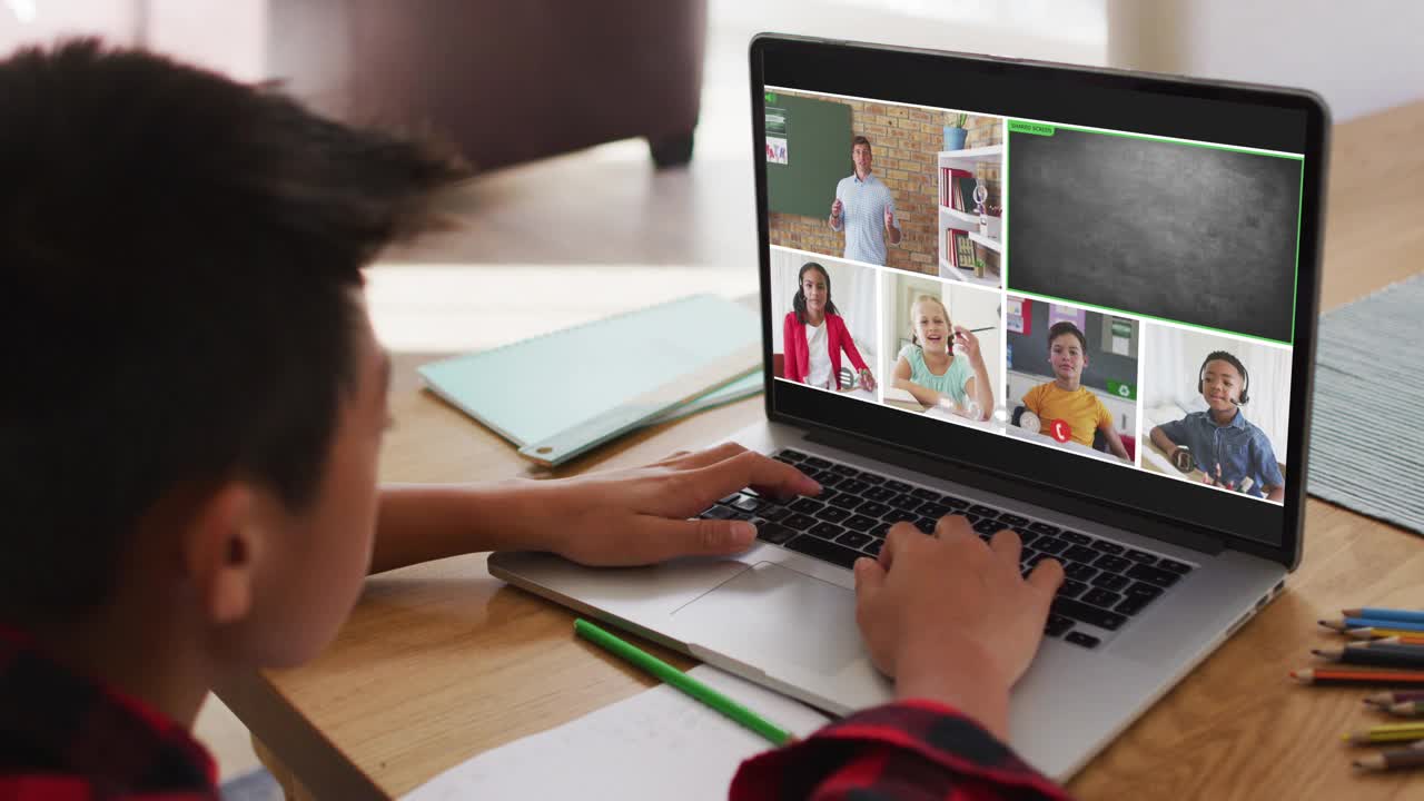 一个亚洲男孩在家里用笔记本电脑与老师和同学进行视频会议