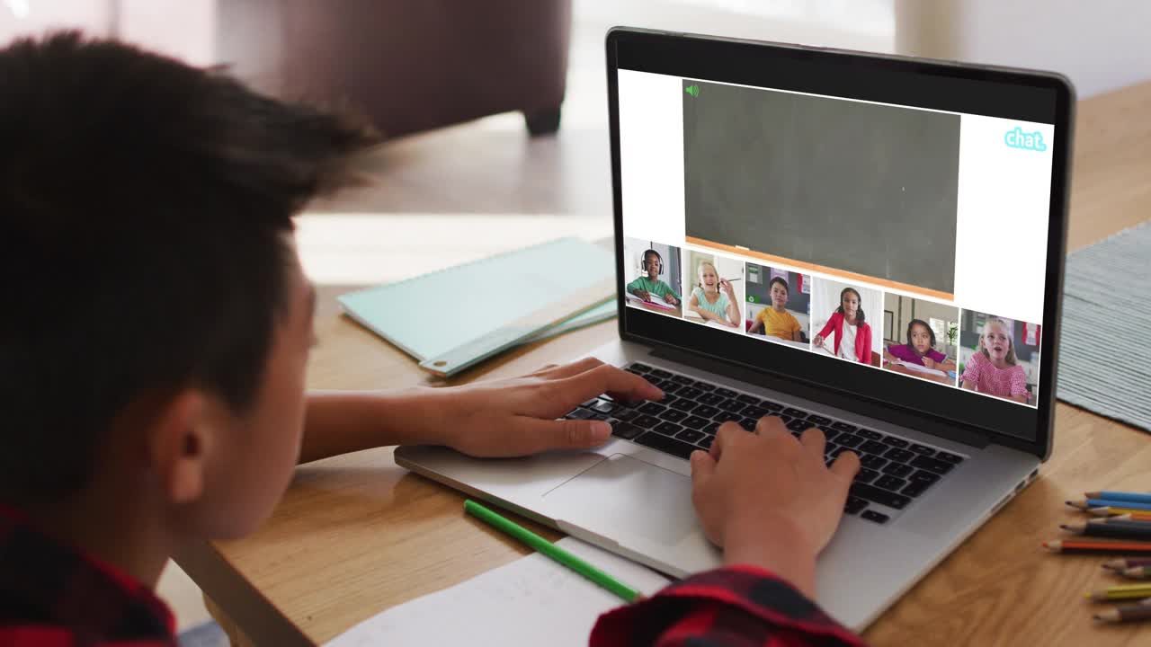 一个亚洲男孩在家里用笔记本电脑与老师和同学进行视频会议