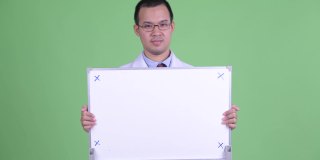 工作室人像亚洲男子医生拿着白板与copyspace在绿色背景