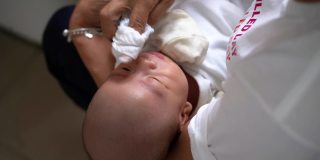 一位亚洲妇女用一块布擦孙子的脸