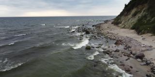 在刮风寒冷的日子里，海浪和石头的岩石被无人机拍摄下来