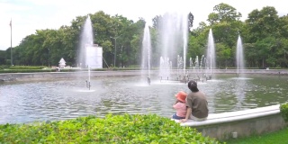 小男孩和妈妈坐在公园里一起看喷泉