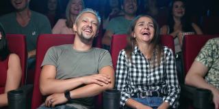 大笑的夫妇有乐趣的积极情绪，在电影院看喜剧电影，坐在一排观众
