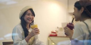 年轻的亚洲女性朋友在城里的咖啡店见面