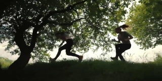 两个女孩在树下奔跑，跑步时摔倒的运动员，侧视，城市背景。晨跑。落在运行