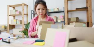 年轻的亚洲企业家女商人检查产品采购订单库存和保存到平板电脑工作在家里的办公室。