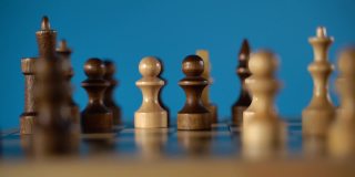 国际象棋在蓝色背景上的特写。木质棋子。概念:棋盘游戏和智力活动