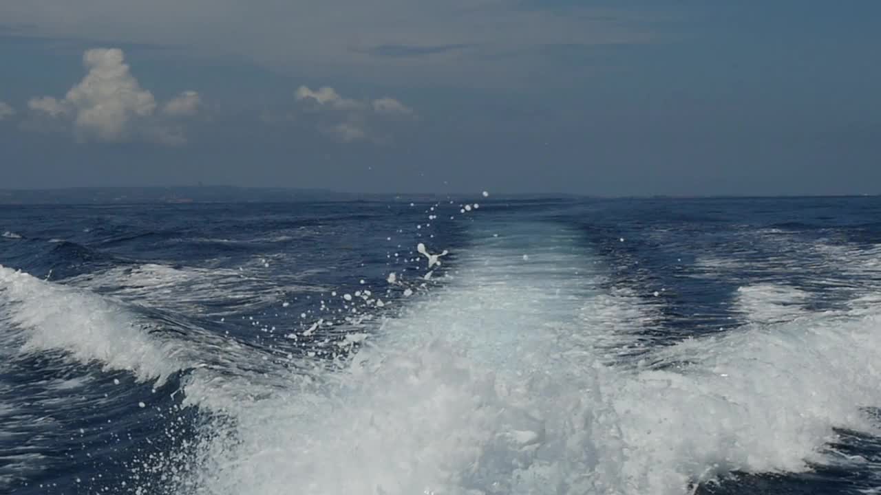 在印度尼西亚，一艘摩托艇发出的波浪以海洋地平线为背景。