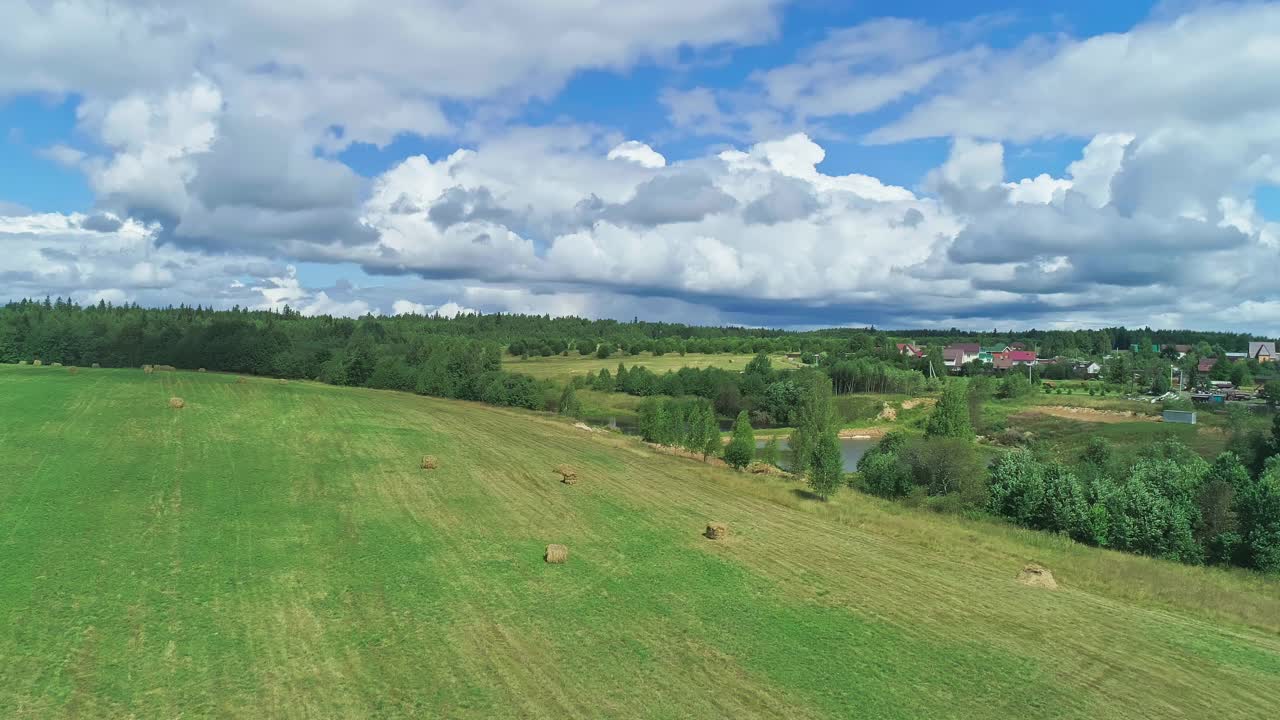 田园诗般的乡村。草地，干草田，村庄，大片白云。