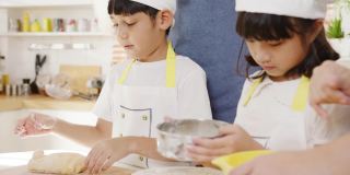 快乐微笑的年轻亚洲日本家庭与学龄前的孩子有乐趣在现代厨房家庭的早餐烘焙糕点或派。