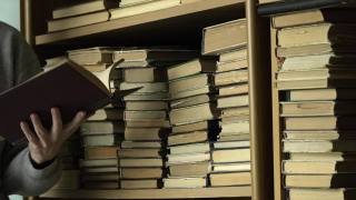 书架上有旧书。一位妇女在图书馆的书架上寻找一本书。人类选择书籍。白种人用手触摸书架上的书。阅读观念与教育视频素材模板下载