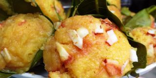 传统的蒸熟棕榈水果蛋糕，包裹着菠萝蜜叶子，撒上椰子片。近距离观察蒸棕榈饼。4 k的视频。