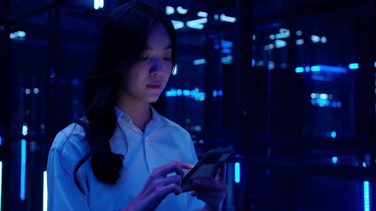 一名亚洲少女在夜晚使用5G移动智能手机，在五颜六色的紫外线灯下观看。移动互联网，新一代网络。可视化5 g的概念。
