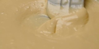 女人们用橡皮刮刀将面粉、鲜奶和鸡蛋搅拌在一起，准备制作自制煎饼的面糊。烹饪过程。