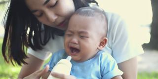 亚洲母亲带着哭泣的男婴在公园里