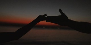 手在夕阳的天空下跳舞。海景浪漫