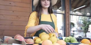 开朗的女蔬菜水果商在农贸市场提供本地产品