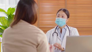 专业的亚洲女医生为患者提供健康咨询，为健康生活提供健康咨询，在医院穿着白大褂带着听诊器与患者交谈，医生和患者的概念视频素材模板下载