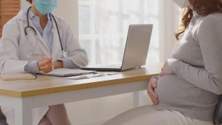 专业的亚洲女医生咨询孕妇，聪明的医生穿着白大褂，带着听诊器在医院与病人交谈，医生和孕妇的概念视频素材模板下载