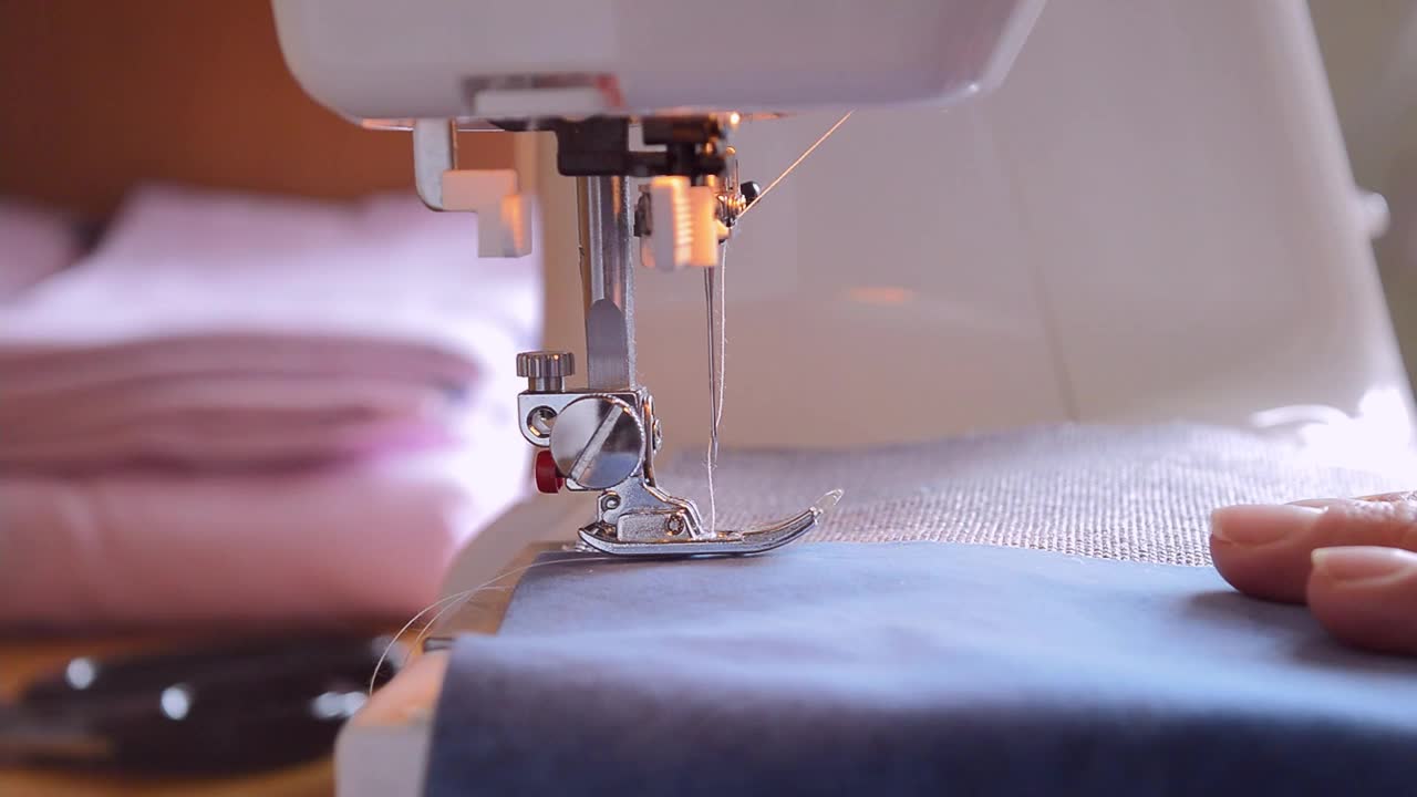 特写镜头:针穿面料，缝纫机脚放低，缝纫过程。
