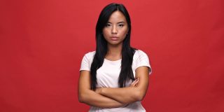 不高兴的亚洲女人在t恤，抱着交叉的双臂不同意的事情