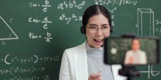 年轻的亚洲女教师站在摄像机和学生视频会议。女教师在课堂上通过智能手机在线课程直播培训数学。