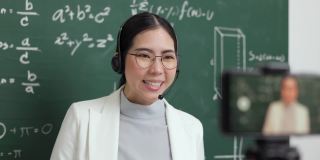 年轻的亚洲女教师站在摄像机和学生视频会议。女教师在课堂上通过智能手机在线课程直播培训数学。