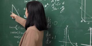 年轻的亚洲女教师与学生在摄像机视频会议上讲话。女教师在课堂上培训数学黑板在线课程。