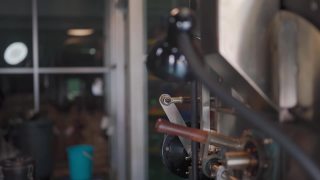 亚洲华人高级技工微笑着拿着特里尔从咖啡烘焙机中提取咖啡豆烘焙生咖啡豆闻检查视频素材模板下载