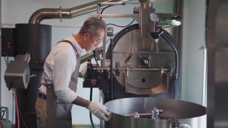 一位亚洲华裔高级技工在他的工厂检查烘培咖啡豆的冷却过程视频素材模板下载