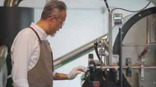 亚裔华裔高级技工操作咖啡烘焙机的控制面板触摸屏，为咖啡烘焙过程做准备视频素材模板下载