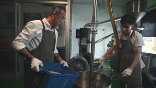 亚洲华人工人将生咖啡豆装入咖啡烘焙机，为咖啡烘焙过程做准备视频素材模板下载
