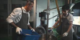 亚洲华人工人将生咖啡豆装入咖啡烘焙机，为咖啡烘焙过程做准备