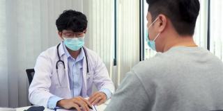 在疫情期间，医生们正戴着口罩讲解病人的治疗方法。