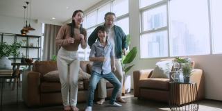 幸福亚洲家庭一起在家里客厅跳舞，亚洲爸爸妈妈和儿子运动锻炼身体周末早上在家隔离禁闭期间
