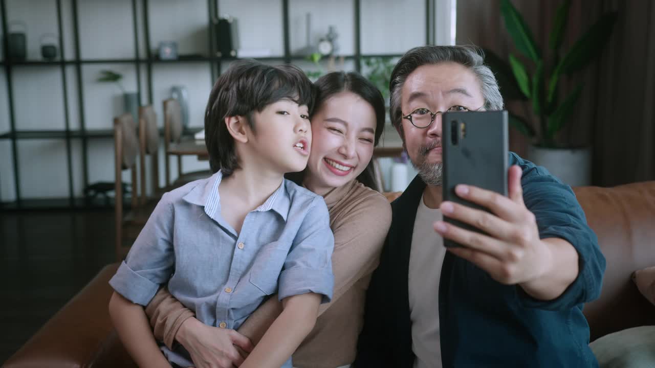 幸福甜蜜的亚洲家庭爸爸妈妈和儿子坐在沙发上视频打电话给爷爷奶奶。笑笑亚洲家庭居家隔离隔离时刻在封锁国家秩序。