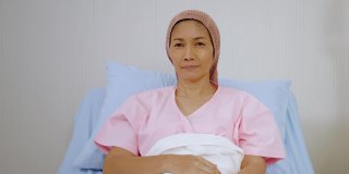 老年女性癌症患者在医院病床上自信地竖起大拇指，概念健康护理，健康保险，人寿保险。