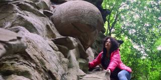 一个女孩拿着一块圆形的石头在岩石上进行地质勘探