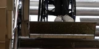 一个残疾的年轻人坐着轮椅上自动电动斜坡