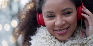 音乐女人听耳机。年轻的非洲裔美国妇女戴着耳机在户外听音乐和摆姿势