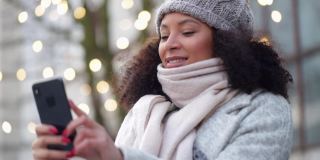 一名女子在冬天的大街上用手机自拍。概念新年，圣诞节