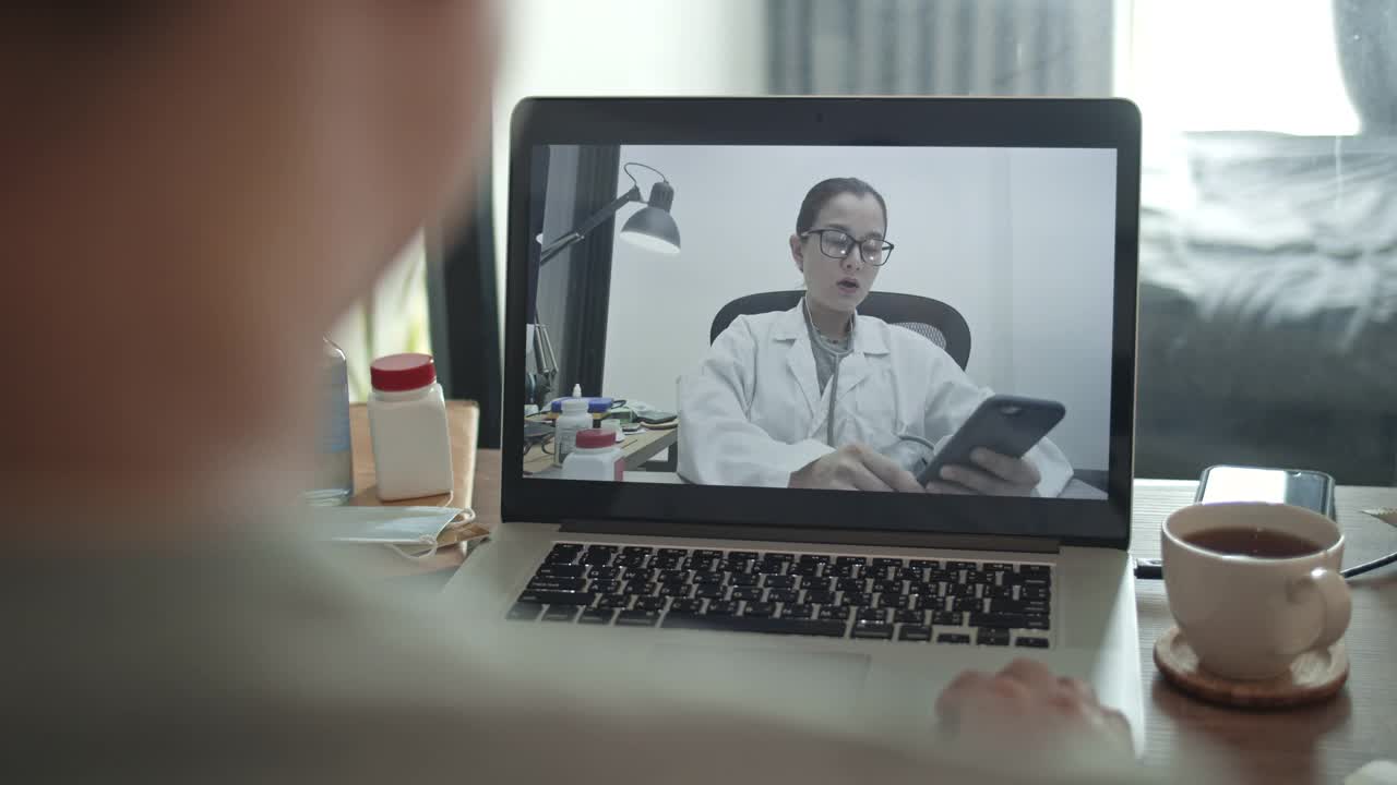 男病人在家里用笔记本电脑与亚洲女医生交谈